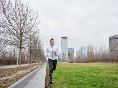 Yetişkin Adam kışın şehir planıyla parkta koşuyor