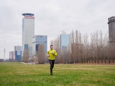 Yetişkin Adam kışın şehir planıyla parkta koşuyor