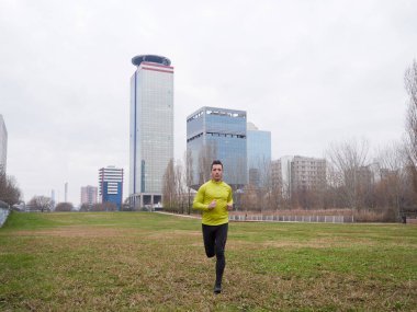 Yetişkin Adam kışın şehir planıyla parkta koşuyor