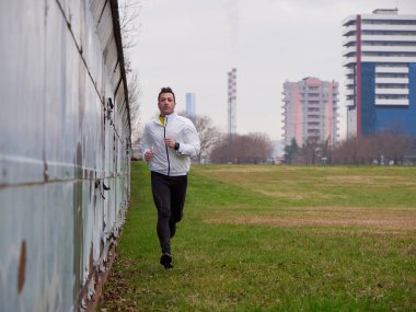 Yetişkin Adam kışın şehir planıyla parkta koşuyor