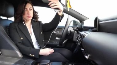 Güzel bir kadın arabanın içinde cep telefonuyla konuşuyor.