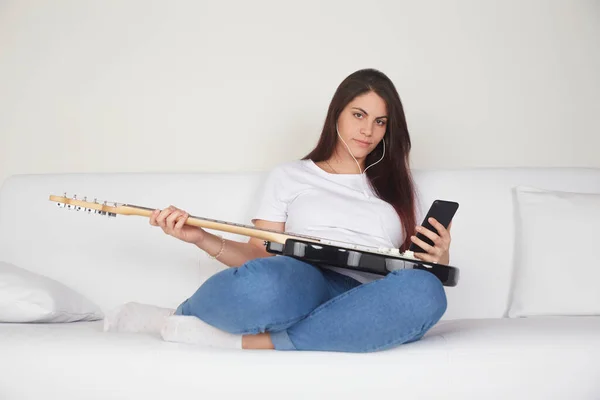 Fröhliches Mädchen Mit Kopfhörern Beobachtet Gitarre Tutorial Auf Dem Handy — Stockfoto