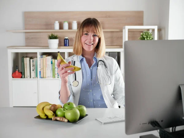 女性栄養士がオフィススタジオでバナナフルーツを保持 — ストック写真