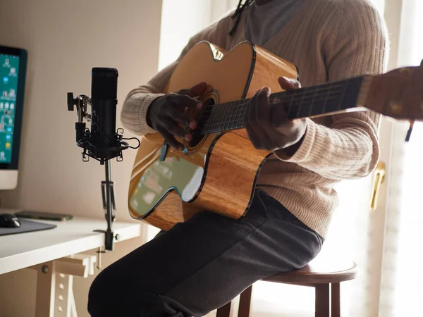 若い男は歌とギターを演奏しながら家で録音をしている — ストック写真