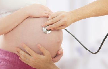 Karın hamile kadın ve doktor bir stetoskop ile el