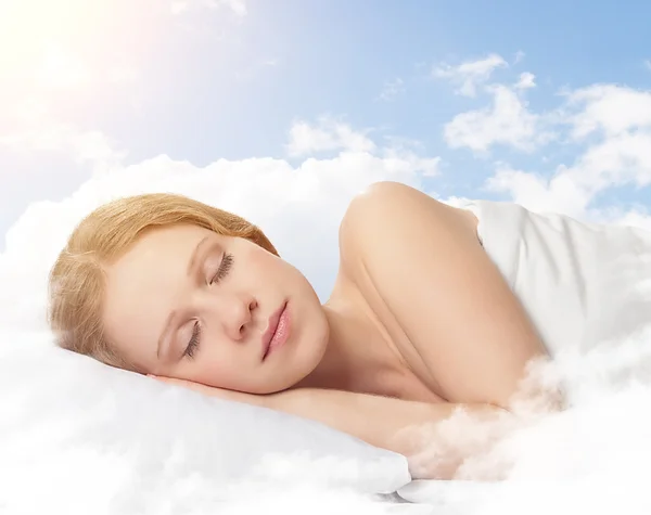 Hermosa joven que duerme en una nube en el cielo — Foto de Stock