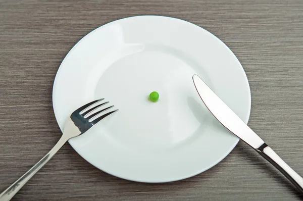 Concepto de dieta. un guisante en un plato blanco vacío —  Fotos de Stock