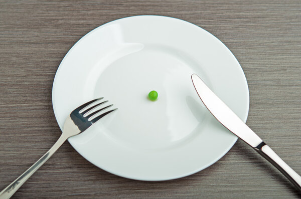 Diet concept. one pea on an empty white plate