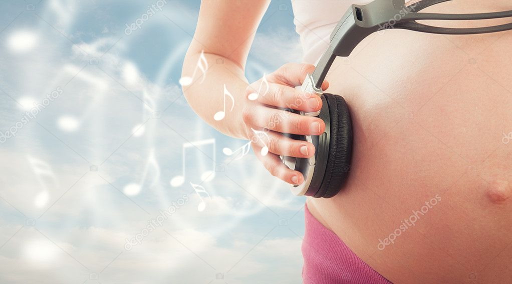 Concept pregnancy and music. belly of pregnant woman and headpho