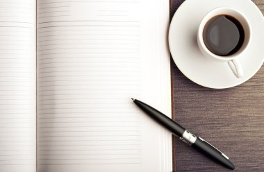 Masanın üzerinde boş bir beyaz defter, kalem ve kahve aç.