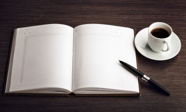 Masanın üzerinde boş bir beyaz defter, kalem ve kahve aç.