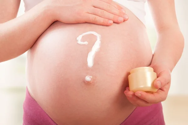 Vientre de la mujer embarazada y signo de interrogación, crema pintada —  Fotos de Stock