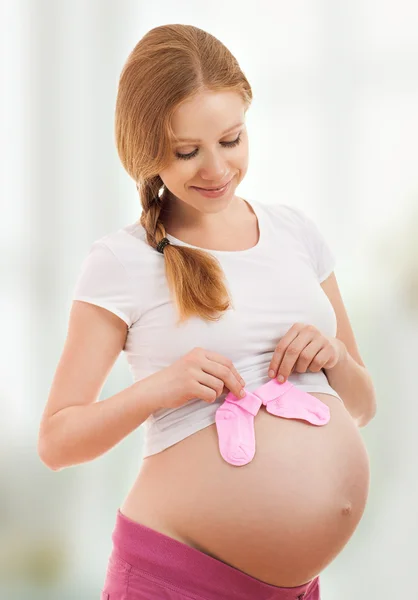 Беременная женщина в синих розовых детских носках — стоковое фото