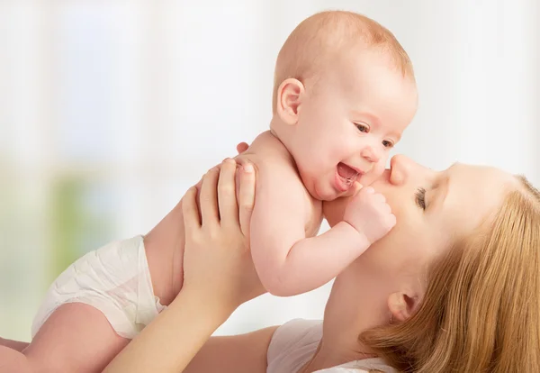 Feliz madre joven besando a un bebé — Foto de Stock