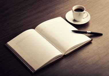 Open a blank white notebook, pen and coffee on the desk