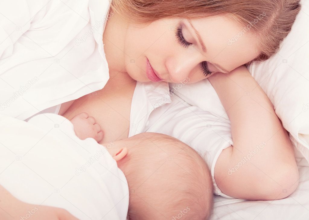 mother feeding her baby in the bed. sleeping together