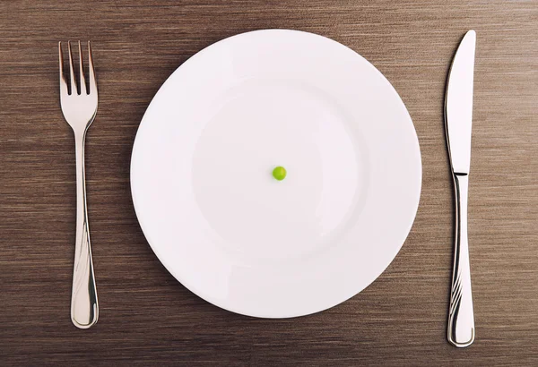Diet concept. one pea on an empty white plate — Stock Photo, Image