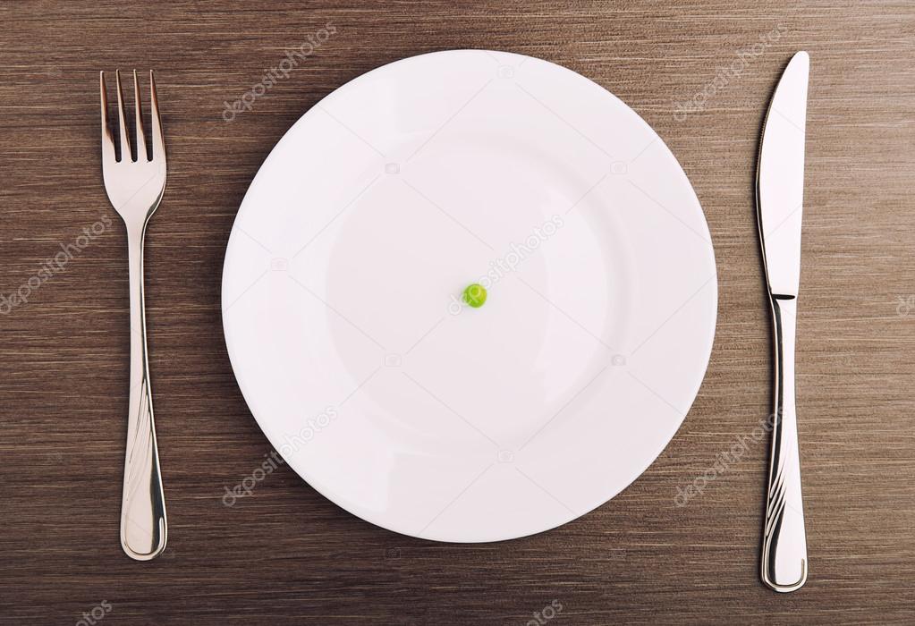 diet concept. one pea on an empty white plate