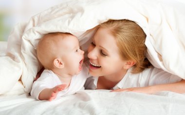 mutlu bir aile. Anne ve bebek battaniye altında oynarken