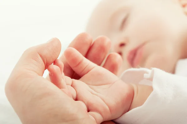 Hand de slapende baby in de hand van moeder Stockfoto