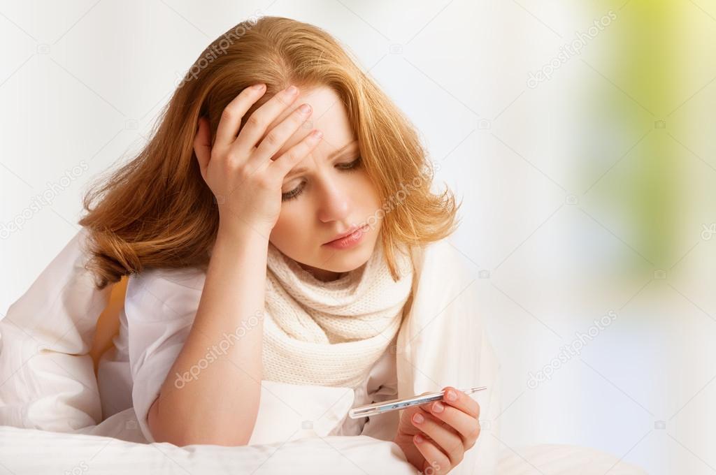 Woman with thermometer sick colds, flu, fever, headache in bed