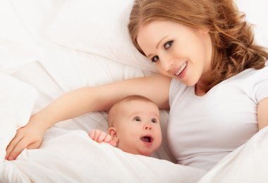 mutlu bir aile. Anne ve bebek yalan ve battaniyenin altında kucaklamak