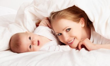 mutlu bir aile. Anne ve bebek battaniye altında oynarken