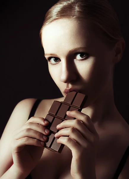Сексуальна красива молода жінка їсть шоколад на темряві — стокове фото