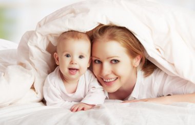 mutlu bir aile. Anne ve bebek battaniye altında oynarken