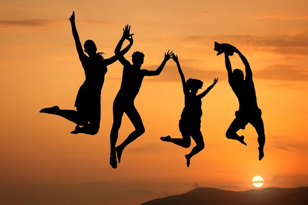 Silhouette of happy jumping at sunset — Stok fotoğraf