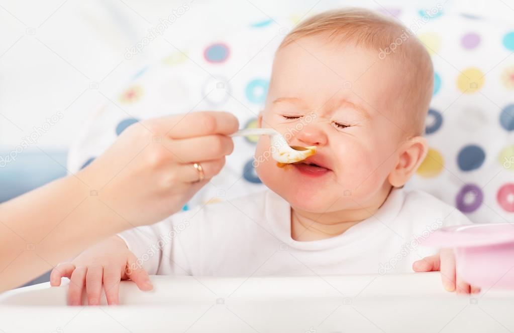 Mom feeds funny baby from spoon