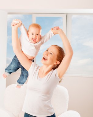 Mother and baby are playing active games, do gymnastics and laug clipart