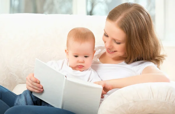 Mãe lendo um livro um bebê no sofá — Fotografia de Stock