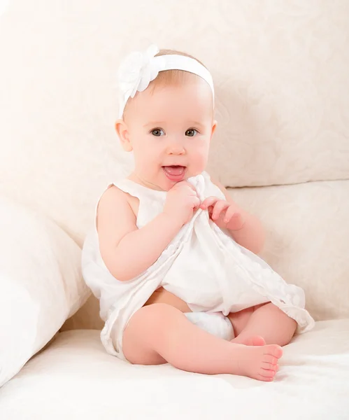 Niña linda en un vestido blanco y con la flor sonriendo — Foto de Stock