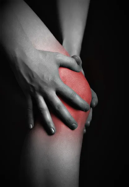 Dor no joelho. Quiroprático fazendo massagem no joelho doente em vermelho — Fotografia de Stock