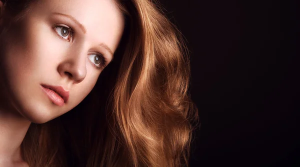 Sad, melancholy girl with long red hair on a dark background — Stock Photo, Image