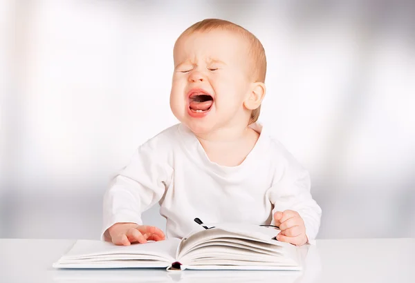 Забавный ребенок читает книгу и плачет — стоковое фото