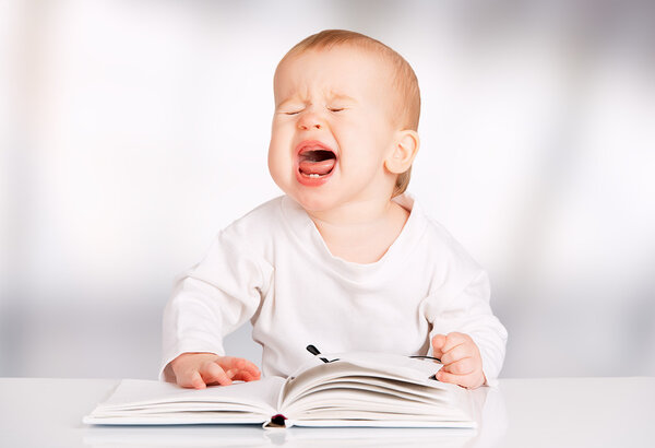 funny baby reading a book and cries