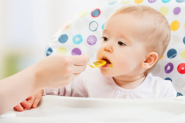 Mãe alimenta bebê engraçado de colher — Fotografia de Stock