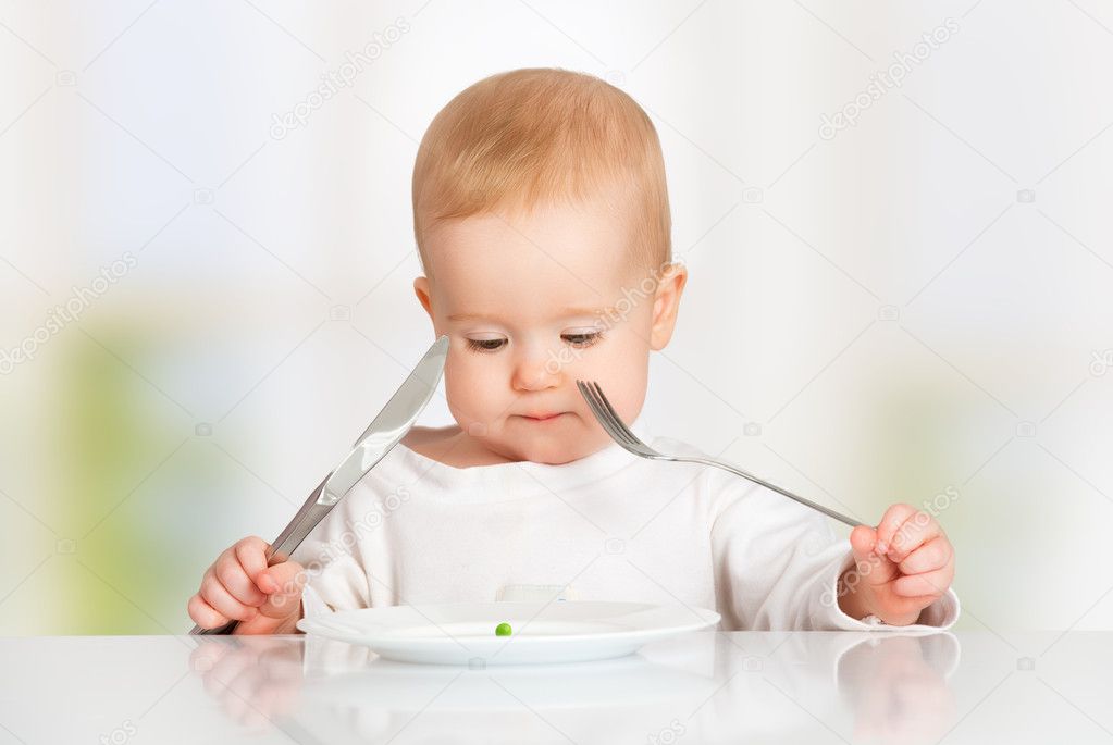 Baby with fork and knife eating, looking at the plate with one p Stock Photo by ©evgenyataman