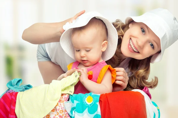 Mom and baby girl with suitcase and clothes ready for traveling — Stock Photo, Image