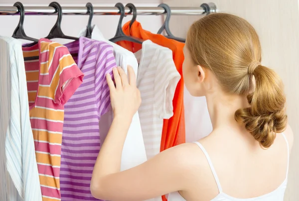 Mulher escolhe roupas no armário do guarda-roupa em casa — Fotografia de Stock