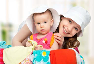 Mom and baby girl with suitcase and clothes ready for traveling clipart