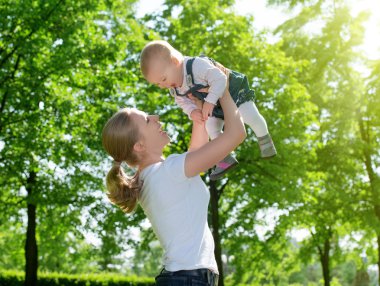 mutlu bir aile. Anne bebek doğa üzerinde yukarı atar.