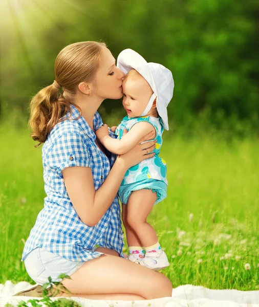 Glückliche Familie auf einem Spaziergang. Mutter küsst Baby — Stockfoto