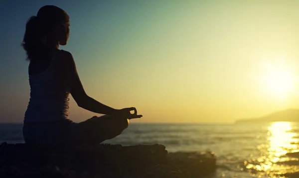 Yoga açık havada. lotus pozisyonda oturan bir kadın silueti — Stok fotoğraf
