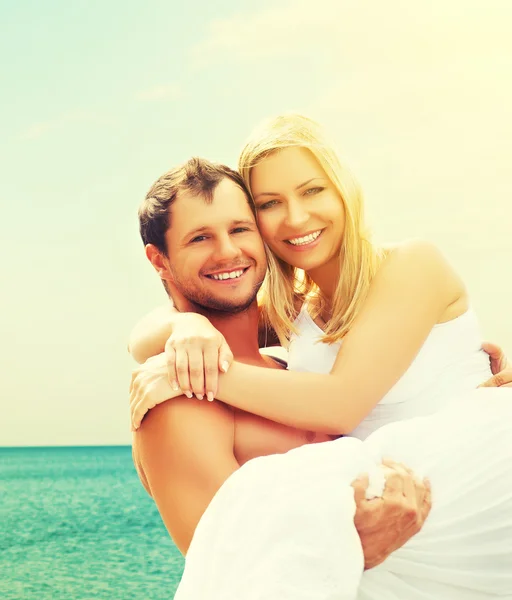 Happy family couple in love hugging and laughing on the beach — Stock Photo, Image