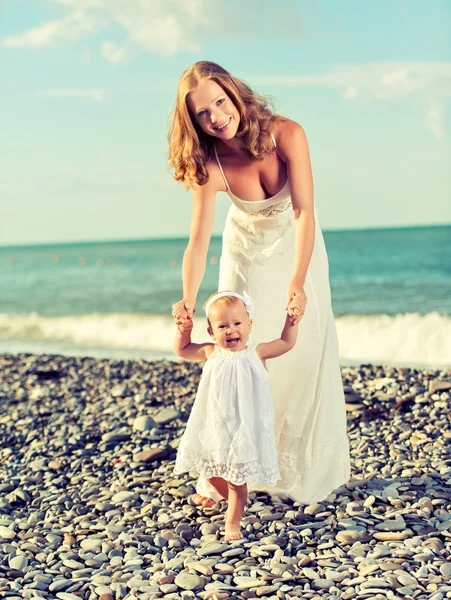 Familia feliz, madre e hija bebé en vestidos blancos en el b —  Fotos de Stock