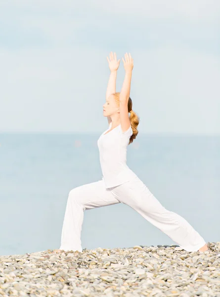 Donna in bianco facendo yoga sulla spiaggia — Foto Stock