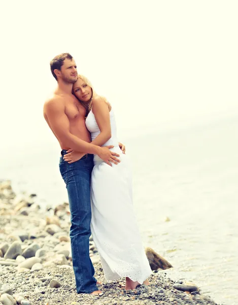 Feliz familia pareja enamorada abrazando y riendo en la playa —  Fotos de Stock